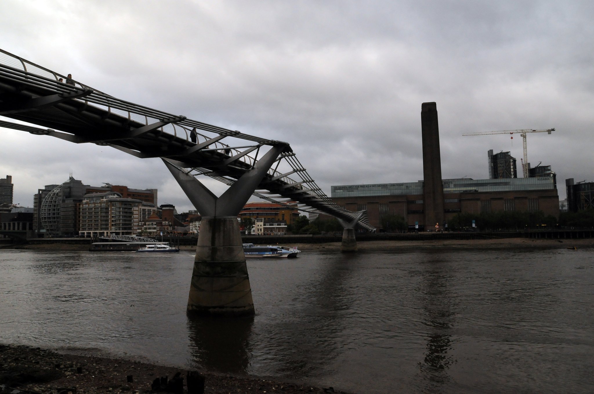 DSC_7483_1.jpg - Millennium Bridge je visutý ocelový most pro pěší přes řeku Temži v Londýně mezi Southwark Bridge a Blackfriars Railway Bridge. Stavba mostu byla zahájena v roce 1998. Náklady na jeho stavbu dosáhly 18,2 miliónů liber a byl otevřen 10. června 2000, ale neočekávané boční chvění zapříčinilo jeho uzavření již 12. června. Kmity byly způsobeny velkým počtem chodců používajících most (90 000 za první den; 2000 chodců v jeden okamžik). Most se nachází na rušné trase a počasí bylo velmi příznivé. Původní malé kmity mostu vedly chodce k tomu aby přizpůsobili svou chůzi jejich frekvenci, což ještě zvyšovalo sílu otřesů. Tento jev vedl k tomu, že most dostal přezdívku klátivý most. Pokusy omezit počet chodců používajících most vedly k vytvoření dlouhých řad a neodstranily kmitání mostu.